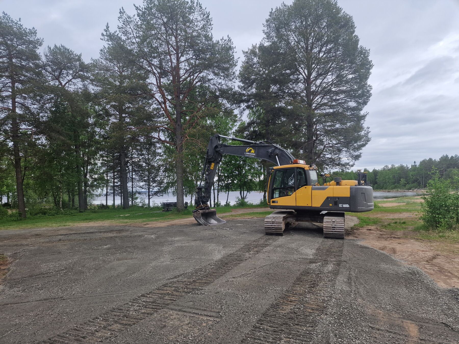 Grävmaskin vid strandkant under markarbete